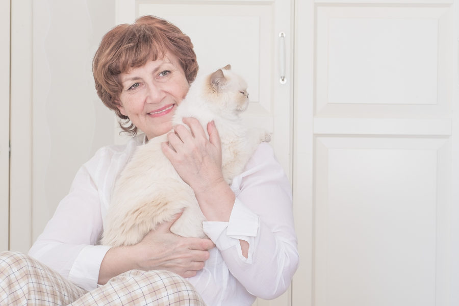 A smiling senior woman enjoying time with her cat.