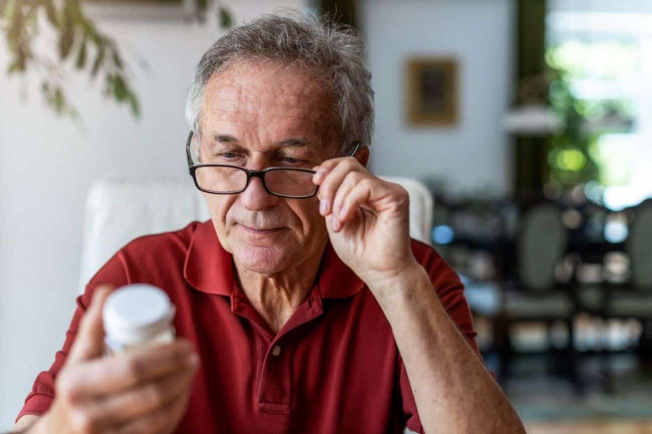a senior male glances at his medication