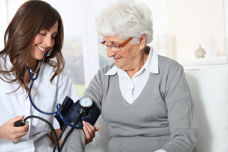 Nurse checking a senior woman’s blood pressure.