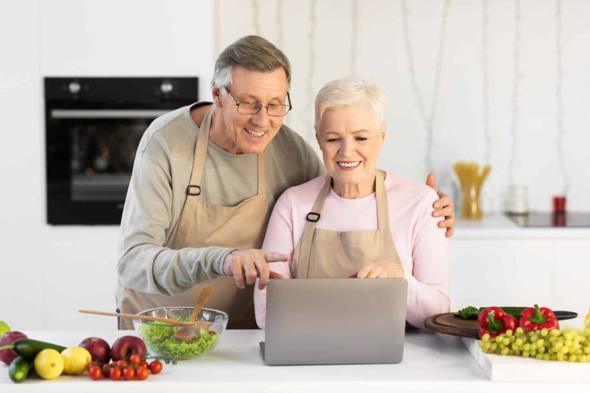 A senior couple enjoy their time indoors by learning a new recipe.
