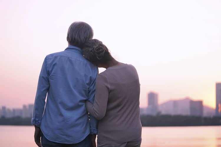 A senior couple embracing while looking over the riverfront.