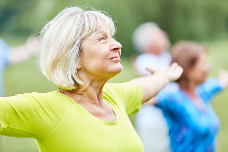 A senior woman experiencing an active lifestyle through an outdoor wellness class.