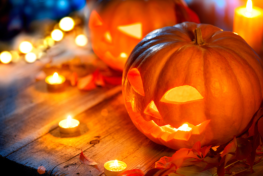 Jack-o-Lantern lit up outside with candles surrounding it