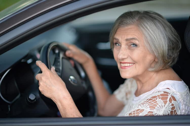 Smiling senior woman driving car.