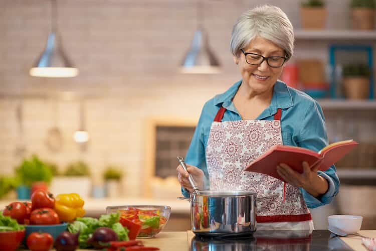 Senior woman cooking a healthy meal in celebration of National Nutrition Month.