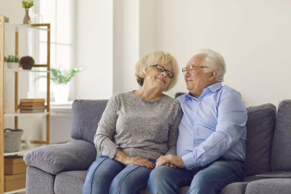 a senior couple sits on a couch together