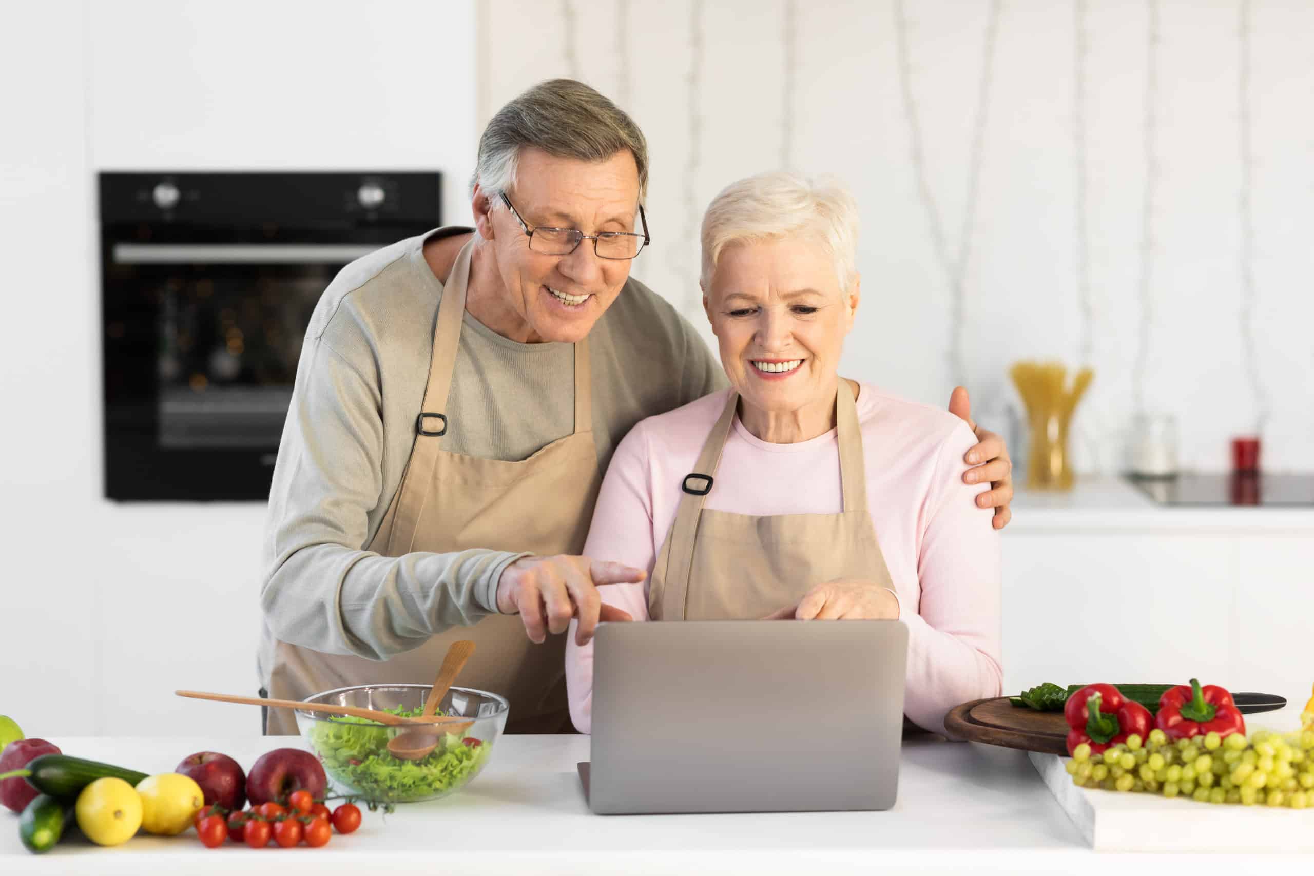 A senior couple enjoy their time indoors by learning a new recipe.
