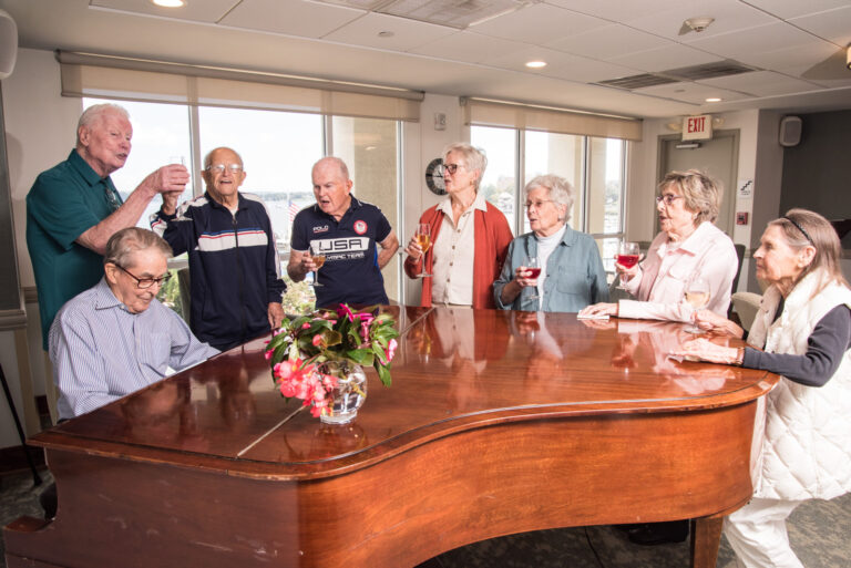 Residents gathered around a Piano singing and smiling