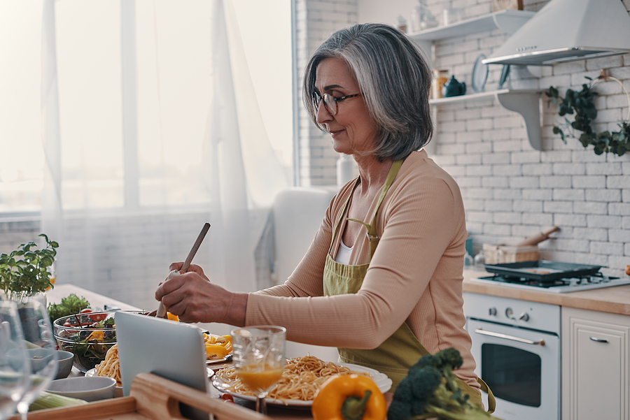 A senior woman cooking in a kitchen.