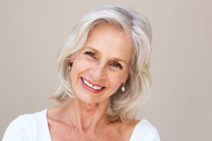 Close up portrait of beautiful older woman smiling and standing by wall