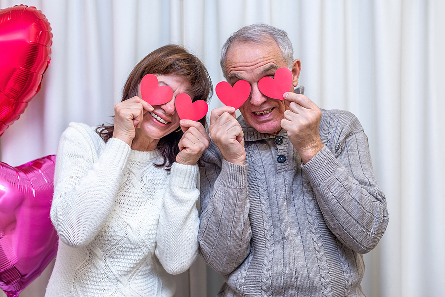 Older adults holding paper hearts over their eyes