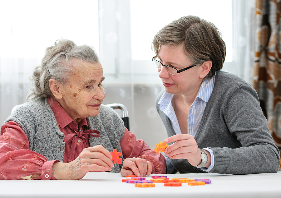 Older adult woman works on a puzzle with an occupational therapist as part of her Parkinson’s care plan
