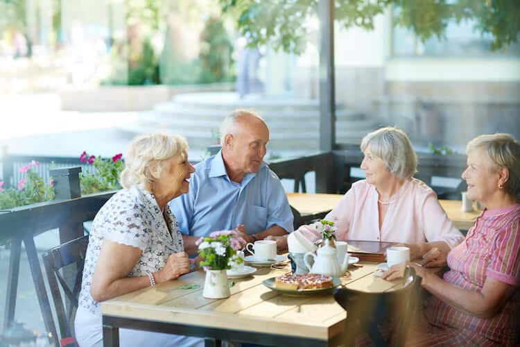 A group of seniors gather at a café table to chat.