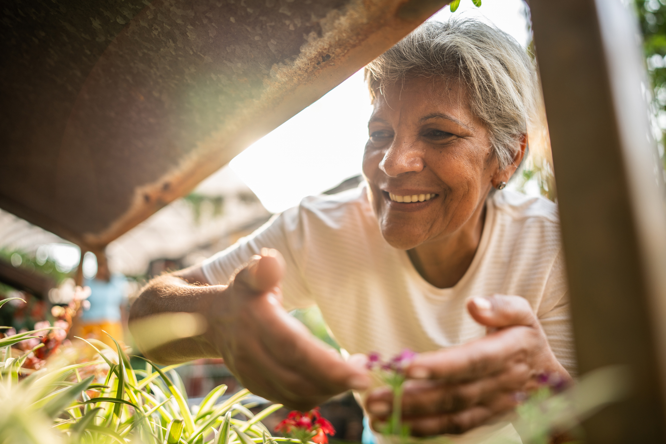 A senior woman smiling as she admires flowers