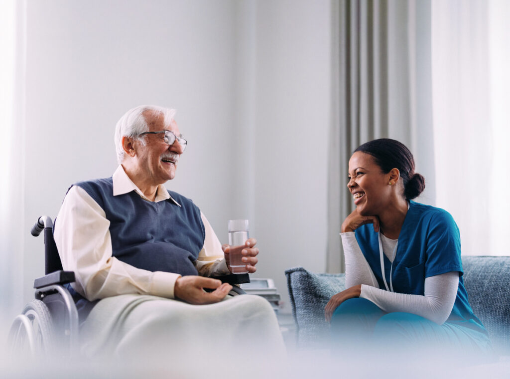 Elderly Man in Wheelchair Smiling at Nurse