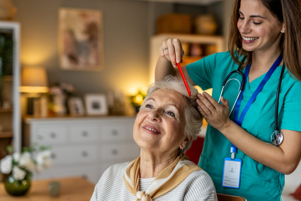 Nursing Brushing Senior Woman's Hair, Both Smiling